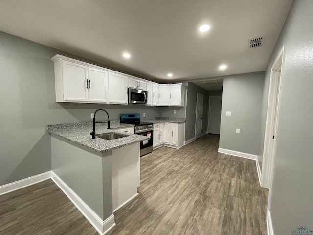 220 Myrle Ave, Longview, TX 75602 - kitchen with appliances with stainless steel finishes, wood finished floors, light stone counters, white cabinetry, and recessed lighting