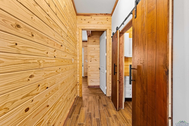 hallway with a barn door, hardwood / wood-style floors, and wood walls