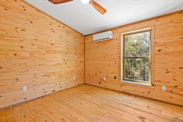 unfurnished room with vaulted ceiling, an AC wall unit, wooden walls, ceiling fan, and light hardwood / wood-style flooring