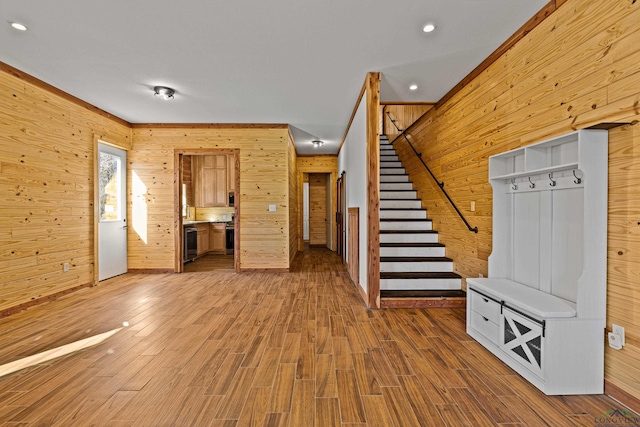 interior space with wood-type flooring, ornamental molding, and wood walls