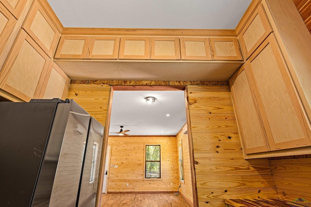 kitchen featuring light hardwood / wood-style flooring, ceiling fan, wooden walls, fridge, and light brown cabinetry