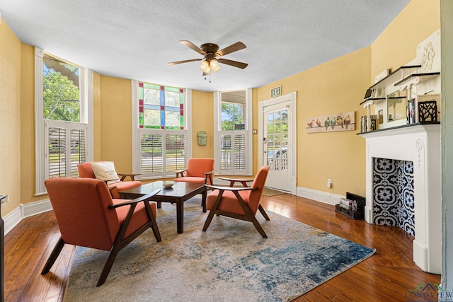 sitting room with wood-type flooring, a ceiling fan, a textured ceiling, and a healthy amount of sunlight