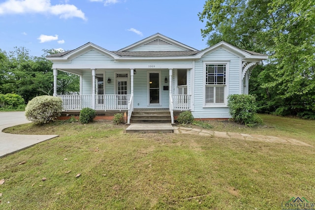 bungalow-style home featuring covered porch, roof with shingles, and a front lawn