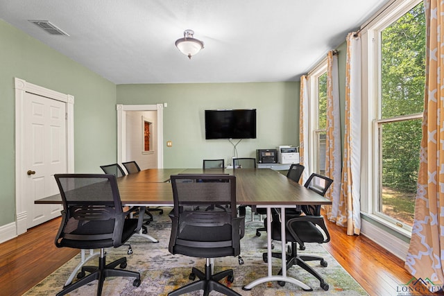 office space with baseboards, plenty of natural light, hardwood / wood-style flooring, and visible vents