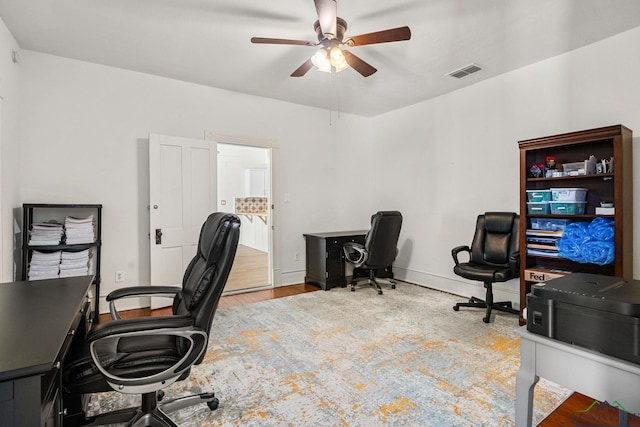 home office featuring baseboards, ceiling fan, wood finished floors, and visible vents