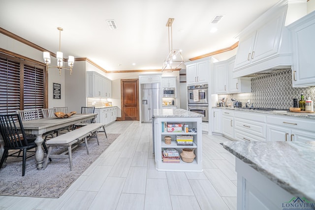 kitchen with white cabinetry, built in appliances, pendant lighting, and light stone counters