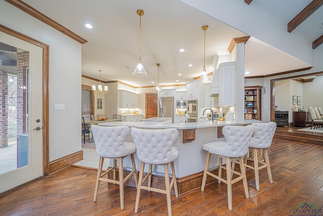 kitchen with hanging light fixtures, white cabinetry, light stone countertops, and dark wood-type flooring