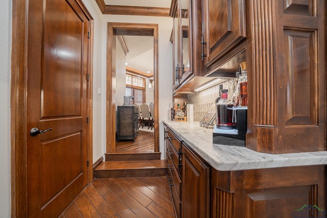 bar featuring crown molding, dark hardwood / wood-style flooring, light stone countertops, and decorative backsplash