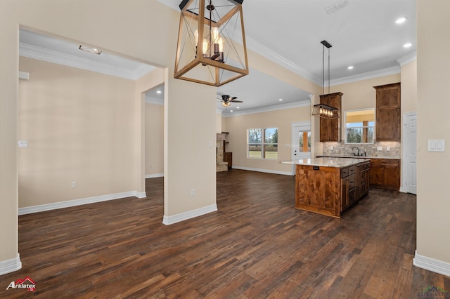 kitchen with backsplash, a kitchen island, open floor plan, a stone fireplace, and ceiling fan with notable chandelier