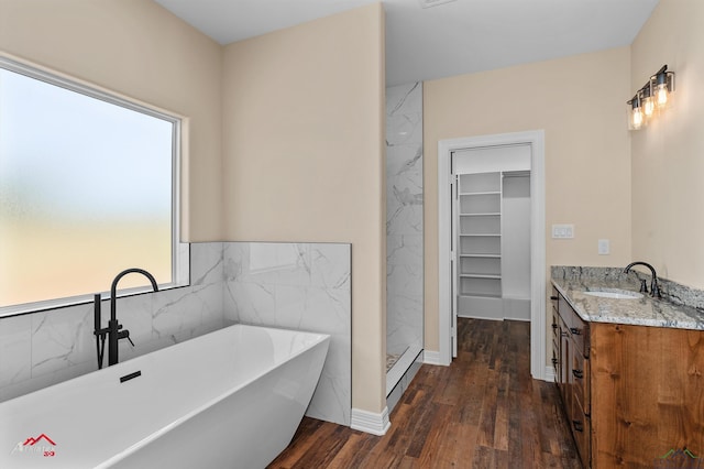 full bath featuring vanity, wood finished floors, a freestanding bath, a shower stall, and a walk in closet