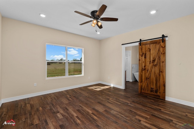 unfurnished bedroom with a barn door, recessed lighting, baseboards, and dark wood-style flooring