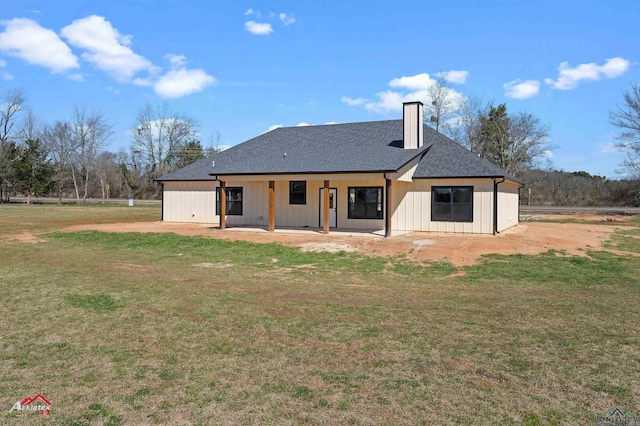 back of property featuring board and batten siding, roof with shingles, a chimney, a yard, and a patio