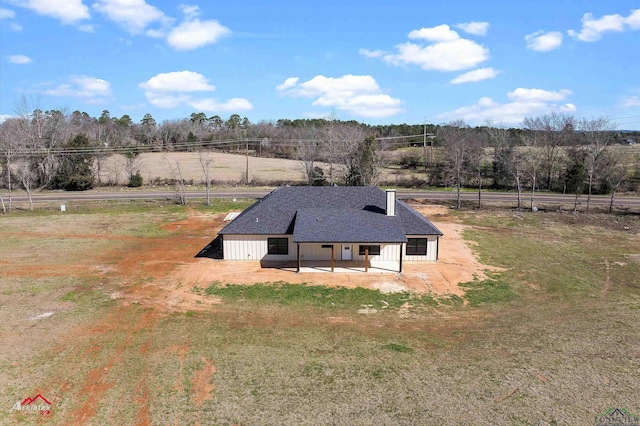 exterior space with a chimney, a rural view, and a shingled roof