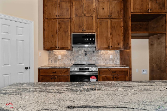 kitchen with tasteful backsplash, stainless steel range with electric cooktop, brown cabinetry, and light stone countertops