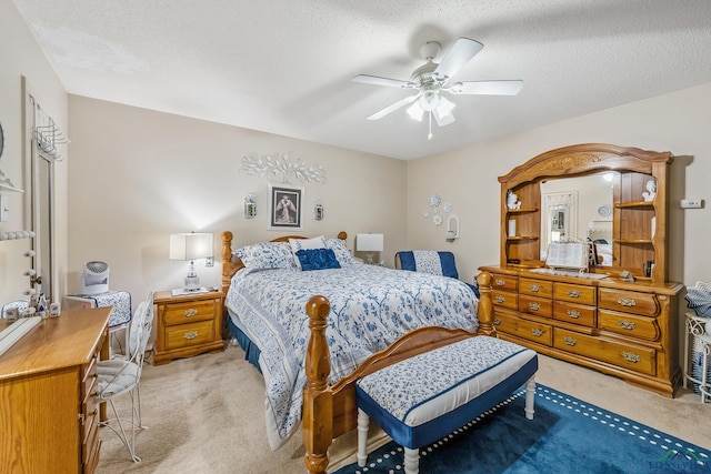 bedroom with ceiling fan, light colored carpet, and a textured ceiling