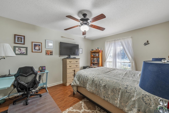 bedroom with hardwood / wood-style flooring, ceiling fan, and a textured ceiling