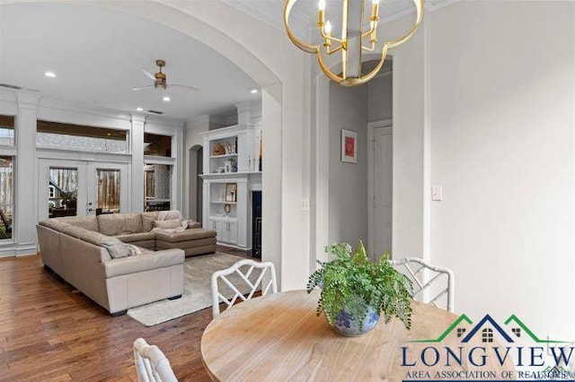 dining area with french doors, dark wood-type flooring, ceiling fan with notable chandelier, and ornamental molding