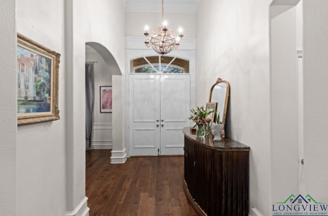 hall with a notable chandelier, dark hardwood / wood-style floors, and ornamental molding