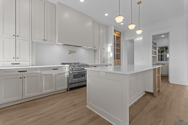 kitchen with a center island, high end stove, light countertops, and white cabinetry