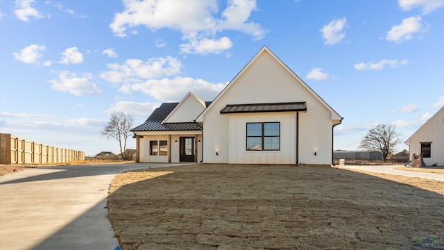 modern farmhouse style home with board and batten siding, a standing seam roof, fence, metal roof, and a front lawn