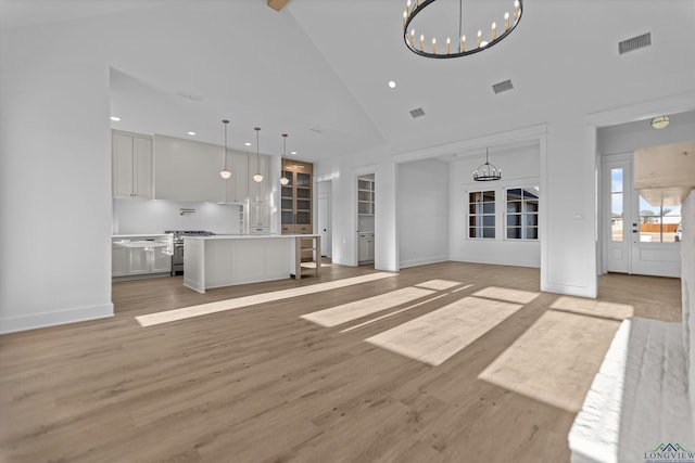 unfurnished living room featuring light wood finished floors, visible vents, high vaulted ceiling, and an inviting chandelier