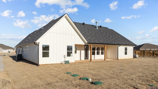 back of house featuring central AC unit, a shingled roof, fence, and board and batten siding