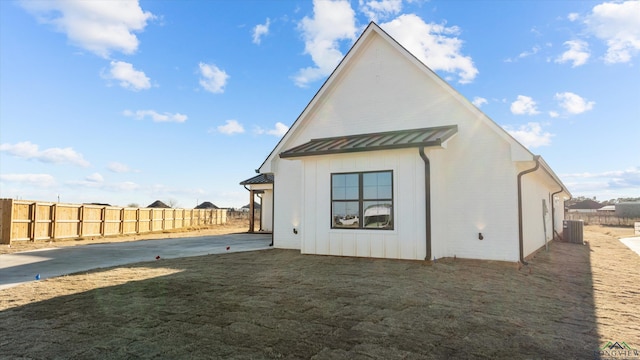 back of house featuring a yard, a standing seam roof, fence, and metal roof