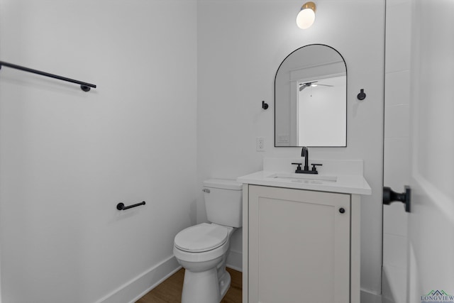 bathroom featuring toilet, baseboards, wood finished floors, and vanity