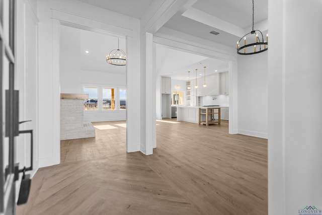 unfurnished living room with baseboards, parquet flooring, visible vents, and a notable chandelier