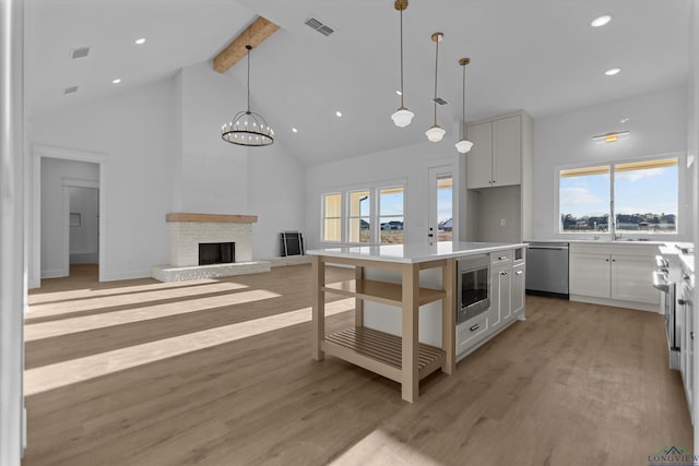 kitchen featuring a kitchen island, white cabinetry, open floor plan, light countertops, and built in microwave