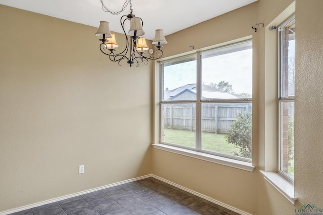 207 Willow Rd, Bullard, TX 75757 - spare room with baseboards, a healthy amount of sunlight, dark tile patterned flooring, and an inviting chandelier