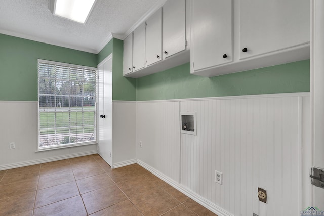 3897 Lansing Switch Rd, Longview, TX 75602 - clothes washing area featuring tile patterned flooring, a textured ceiling, cabinet space, and a wainscoted wall