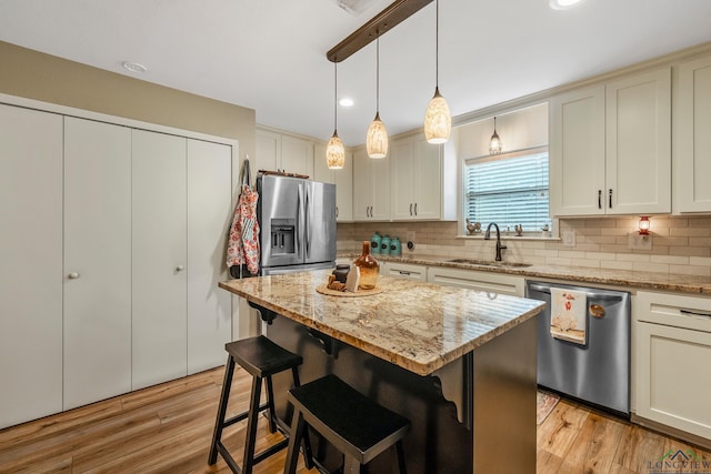 kitchen featuring a kitchen breakfast bar, backsplash, stainless steel appliances, sink, and a center island