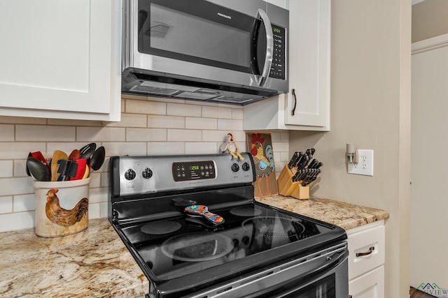 kitchen featuring backsplash, white cabinetry, black / electric stove, and light stone counters