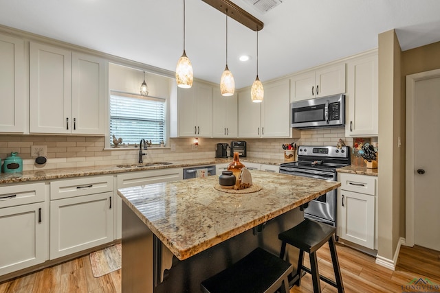 kitchen featuring a kitchen island, light wood-type flooring, sink, and appliances with stainless steel finishes