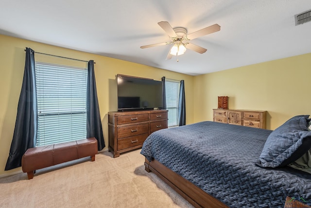 carpeted bedroom featuring multiple windows and ceiling fan