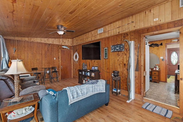 living room with ceiling fan, wood ceiling, wood walls, and light wood-type flooring