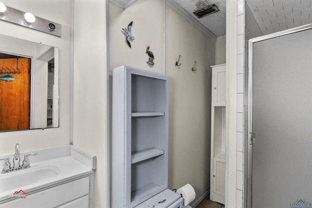 bathroom with a textured ceiling, vanity, and an enclosed shower