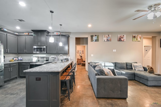 kitchen featuring hanging light fixtures, stainless steel appliances, concrete flooring, a kitchen bar, and gray cabinets