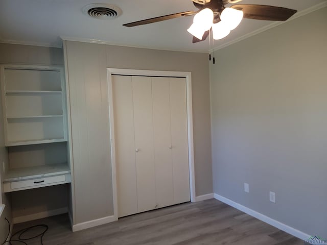711 Wildwood Rd, Daingerfield, TX 75638 - unfurnished bedroom featuring wood finished floors, ornamental molding, a closet, an office area, and a ceiling fan