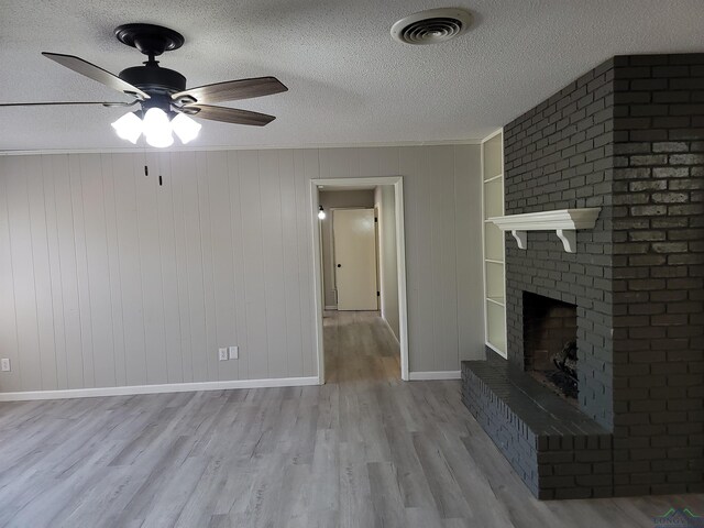711 Wildwood Rd, Daingerfield, TX 75638 - unfurnished living room with a ceiling fan, a brick fireplace, wood finished floors, and a textured ceiling