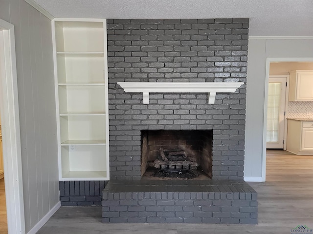 711 Wildwood Rd, Daingerfield, TX 75638 - detailed view of built in shelves, a fireplace, wood finished floors, crown molding, and a textured ceiling