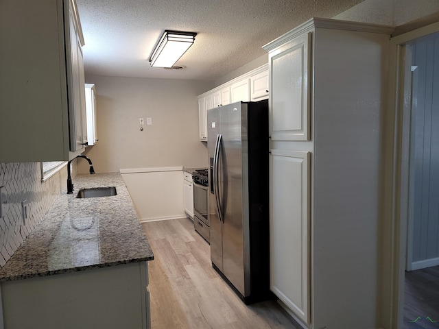 711 Wildwood Rd, Daingerfield, TX 75638 - kitchen featuring appliances with stainless steel finishes, light wood-type flooring, stone counters, a textured ceiling, and white cabinetry