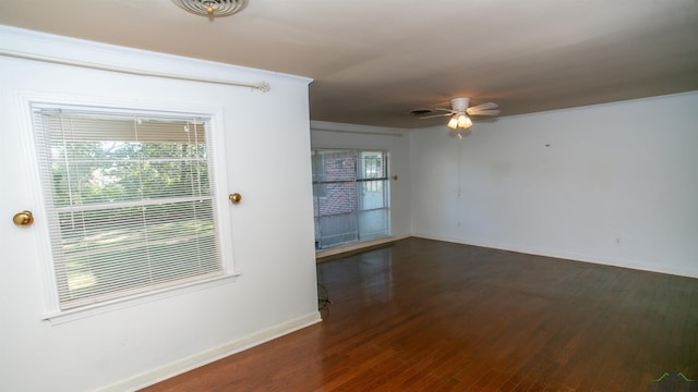 empty room with ceiling fan, dark wood-type flooring, and ornamental molding