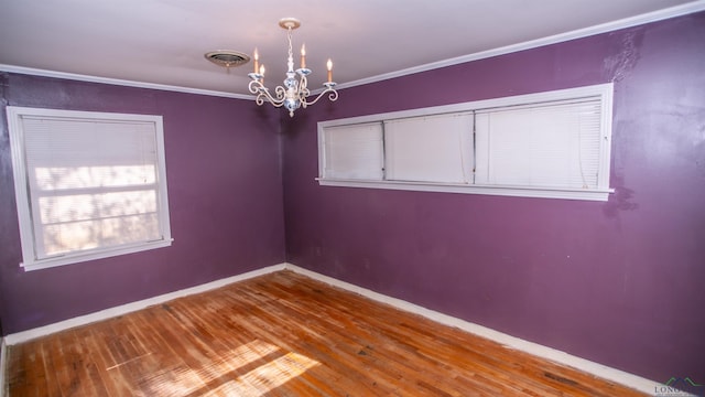 spare room with hardwood / wood-style floors, an inviting chandelier, and ornamental molding