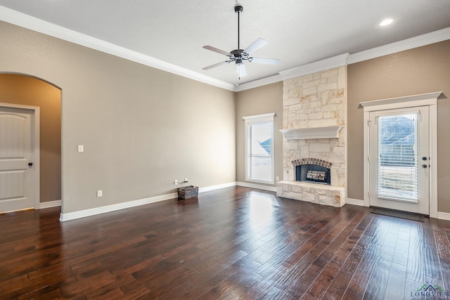 unfurnished living room featuring ceiling fan, dark hardwood / wood-style floors, ornamental molding, and a stone fireplace