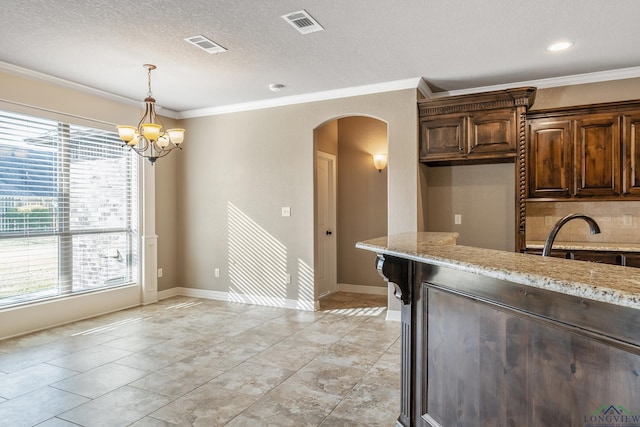 kitchen featuring an inviting chandelier, ornamental molding, hanging light fixtures, and light stone countertops