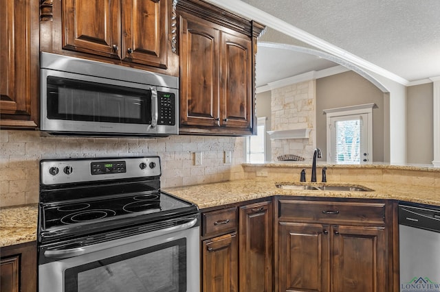 kitchen featuring stainless steel appliances, decorative backsplash, sink, light stone counters, and crown molding