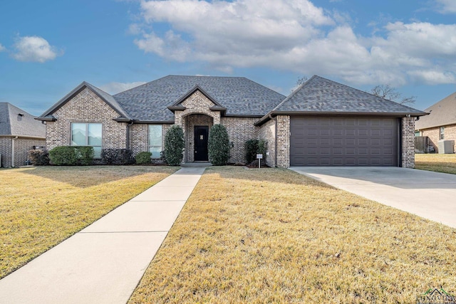 view of front of home featuring a garage, a front yard, and central AC unit