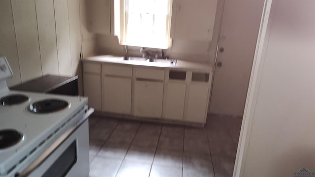 kitchen featuring white electric range oven, dark tile patterned floors, and sink